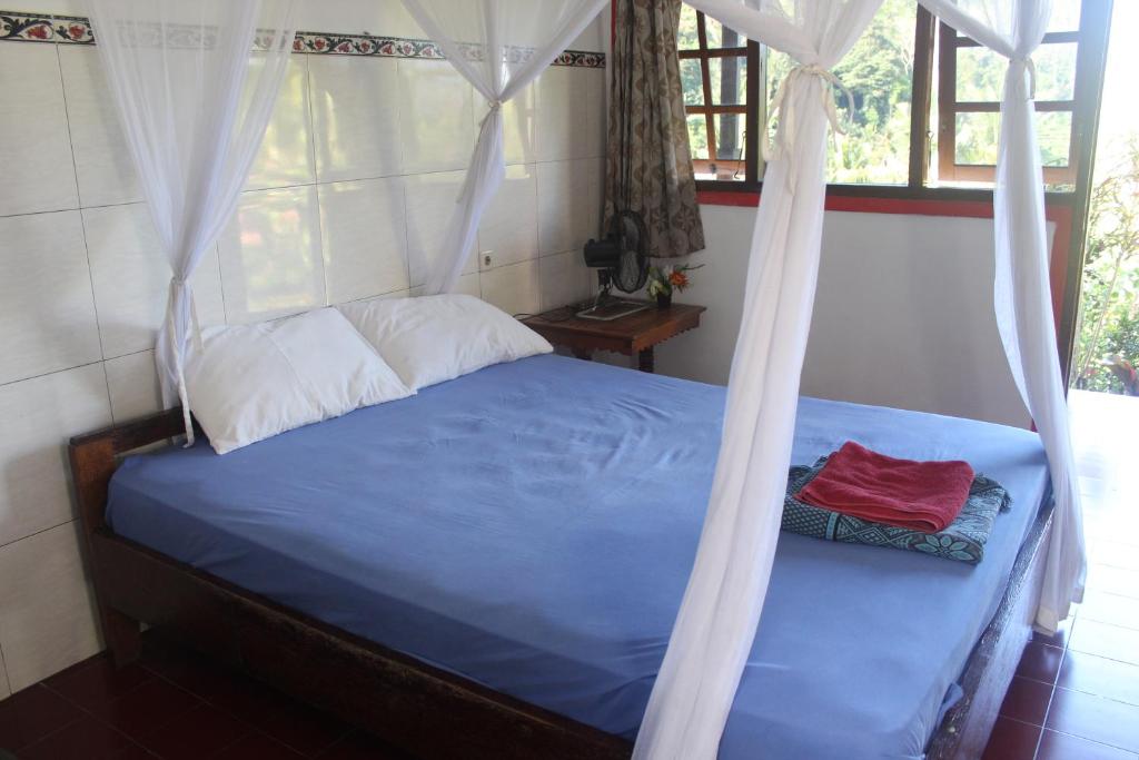 a bedroom with a blue bed with a canopy at Pondok Lembah Dukuh Homestay in Tirtagangga