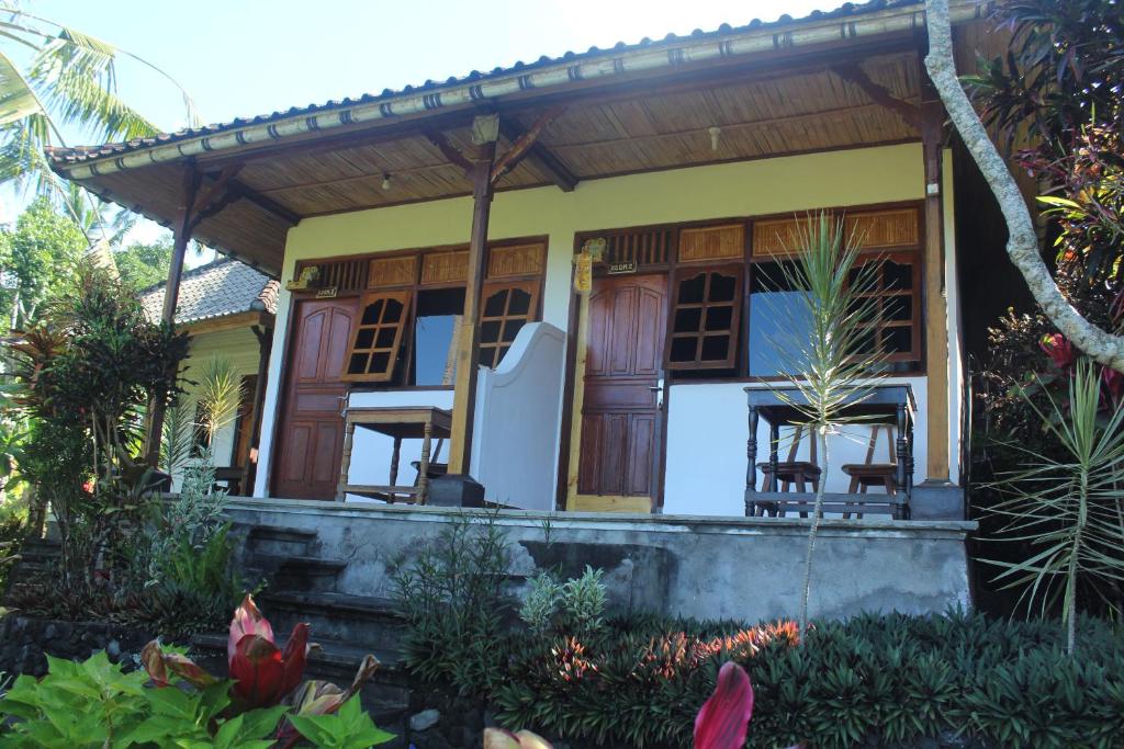 a house with a porch with chairs on it at Pondok Lembah Dukuh Homestay in Tirtagangga
