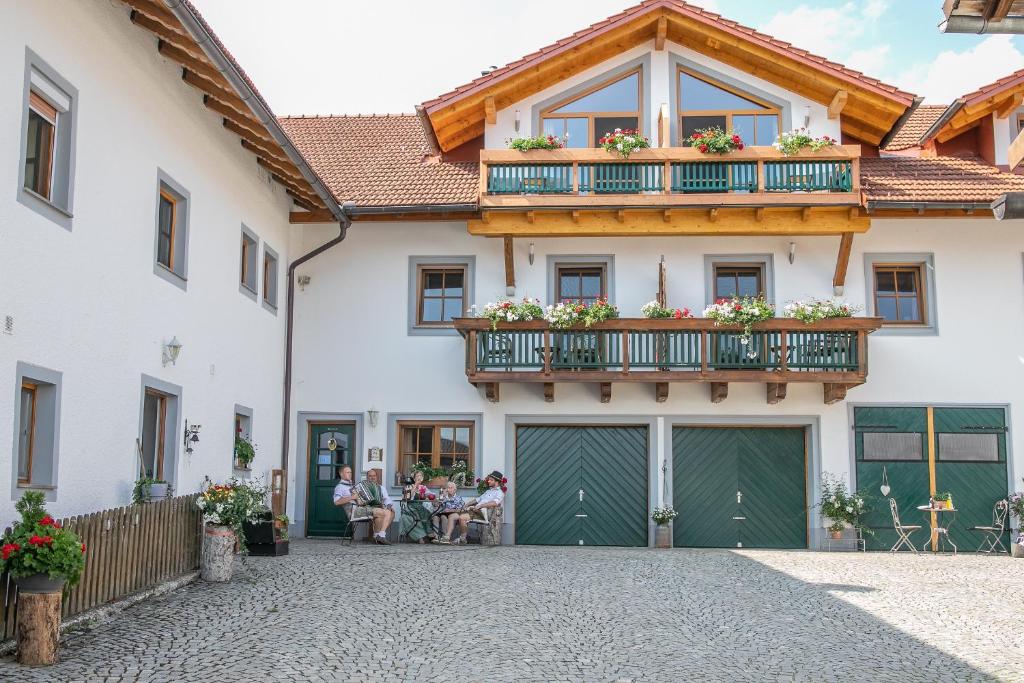 um grupo de pessoas sentadas fora de uma casa em Ferienhof Naderhirn - Bauernhof em Wegscheid