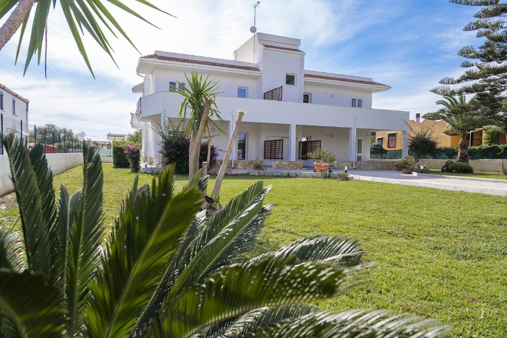 una casa blanca con palmeras en el primer plano en Villa Orietta, en Fontane Bianche