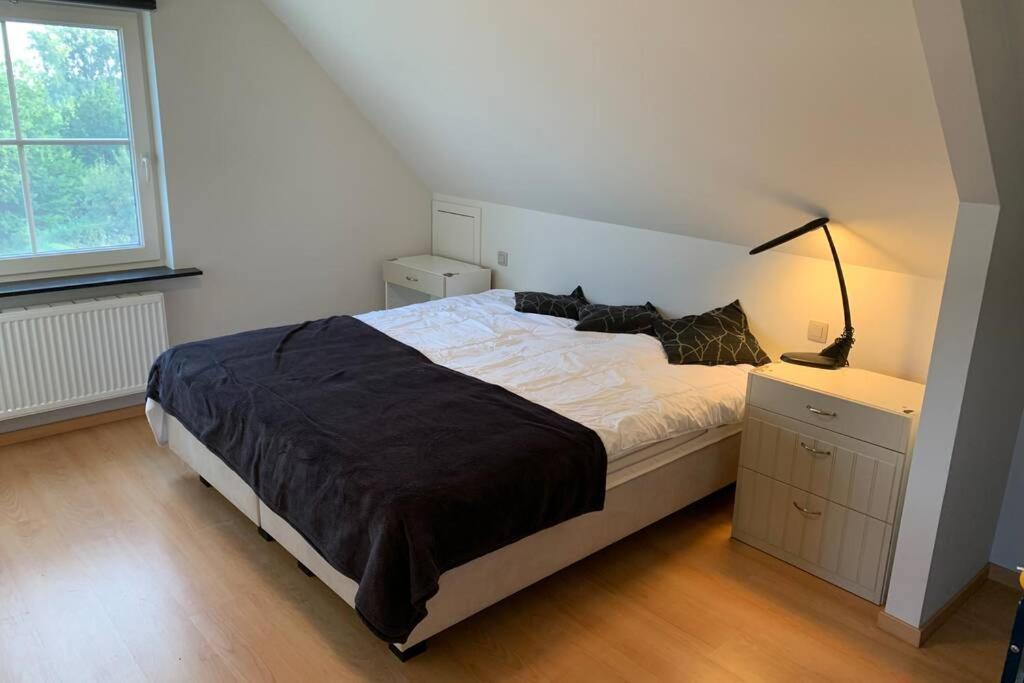 una camera con letto, lampada e finestra di Duplex Appartement Nokeredorp - Vlaamse Ardennen a Kruisem