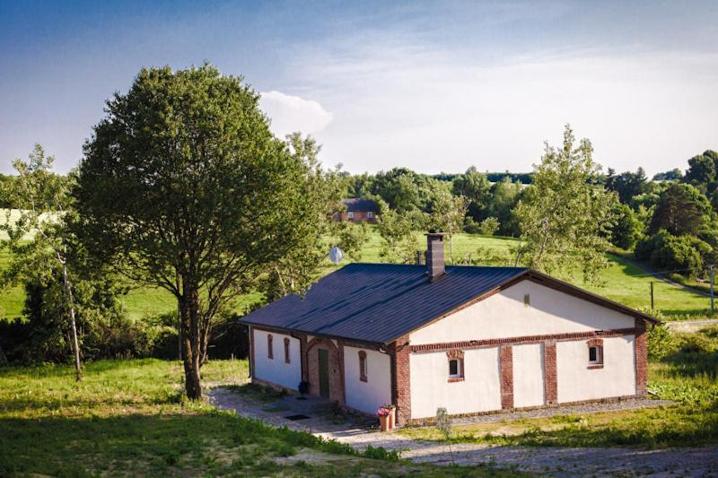 una pequeña casa en un campo con un árbol en Folwark, en Wierzchowiska