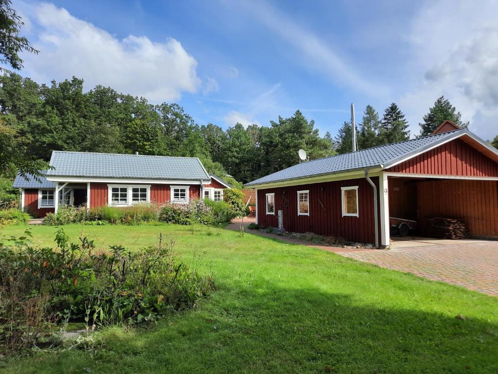 ein rotes und weißes Haus mit einem Rasenhof in der Unterkunft Idyllisches Schwedenhaus in ruhiger Hanglage in Oetzen