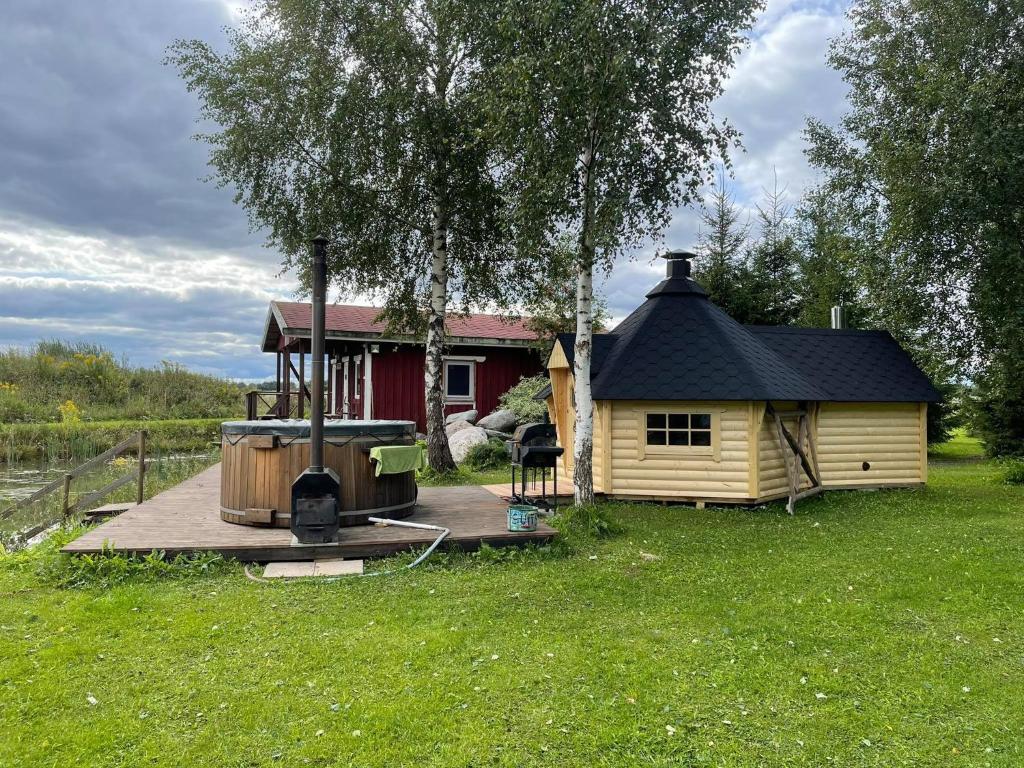 a small cabin with a deck next to a house at Beautiful private cabin near Tartu in Külitse