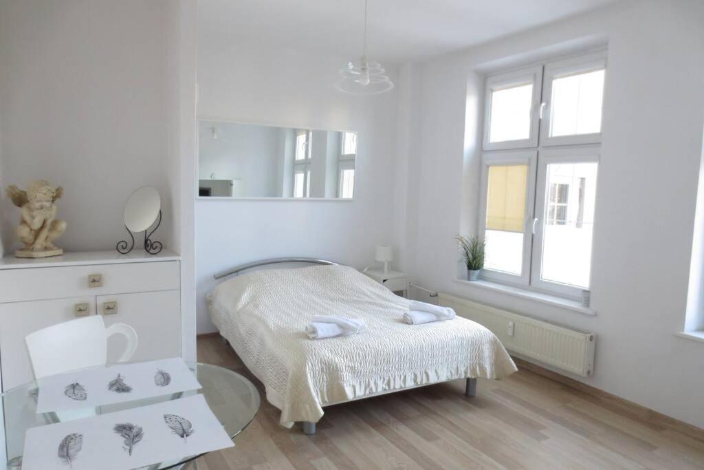 a white room with a bed and a mirror at Apartment Ogarna 35/36 on the Gdańsk Old Town in Gdańsk