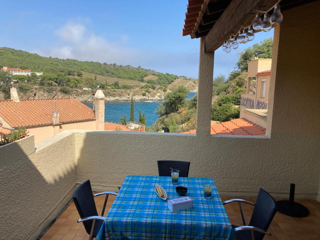 a table on a balcony with a view of the water at T3 PIEDS DANS L'EAU CLIM WIFI TERRASSE VUE MER in Banyuls-sur-Mer