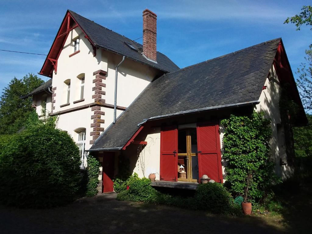 een wit en rood huis met een rode deur bij Ferienbahnhof Utzerath in Utzerath