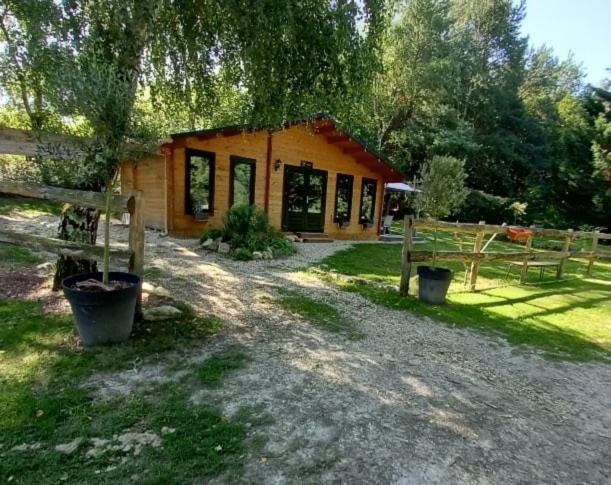 una cabaña de madera con una valla y una casa en Chalet Olivier, en Fléré-la-Rivière