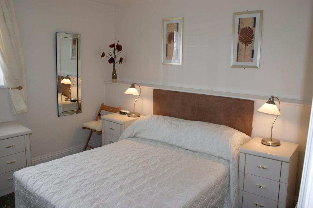 a bedroom with a bed with two lamps and two mirrors at Beachcomber Hotel in Blackpool