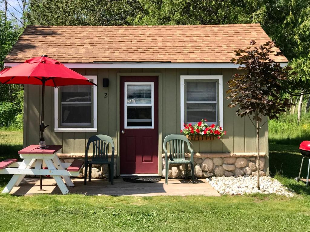 Cedar Ridge Cabins في Honor: منزل صغير مع طاولة نزهة ومظلة