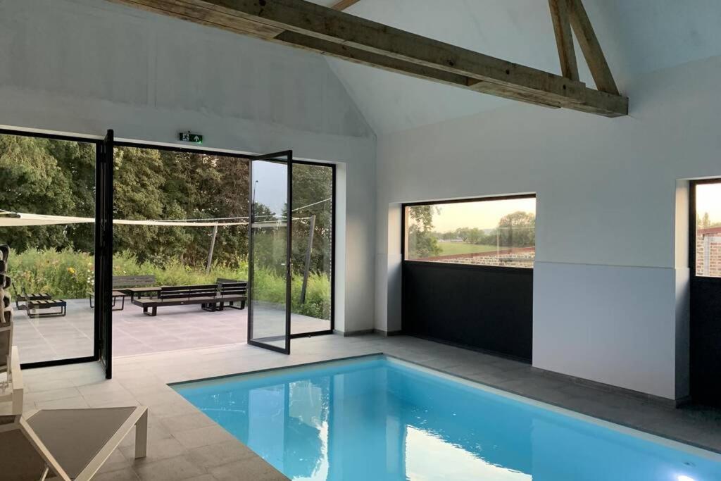 een zwembad in een huis met glazen deuren bij Domein Warandehof in Gooik