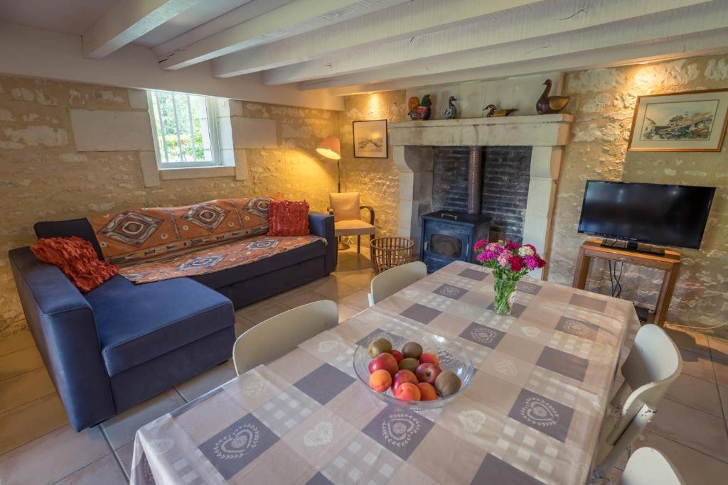 a living room with a table and a couch and a fireplace at Gites Le Clos de Saires in Saires