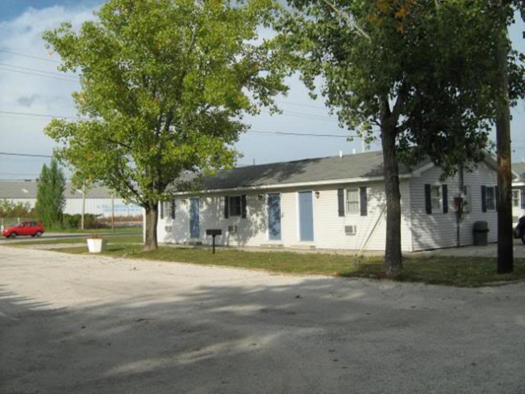 une maison blanche avec des arbres devant elle dans l'établissement White Caps Motel, à Port Clinton