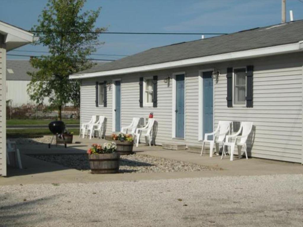 a white house with white chairs in front of it at White Caps Motel in Port Clinton