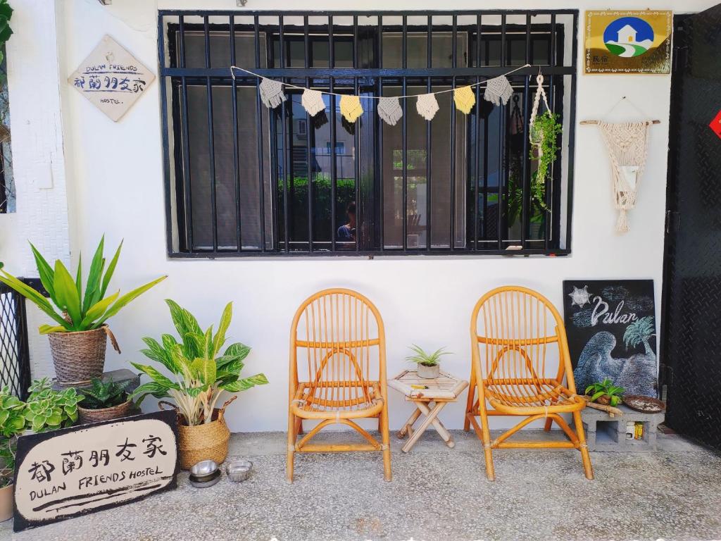 2 sillas sentadas frente a un edificio con ventana en 都蘭朋友家 Dulan Friends Hostel, en Donghe