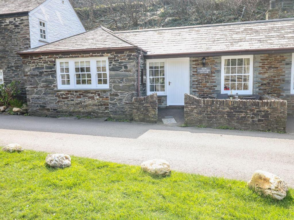 a stone house with a white door and windows at Olde Carpenters Cottage in Boscastle