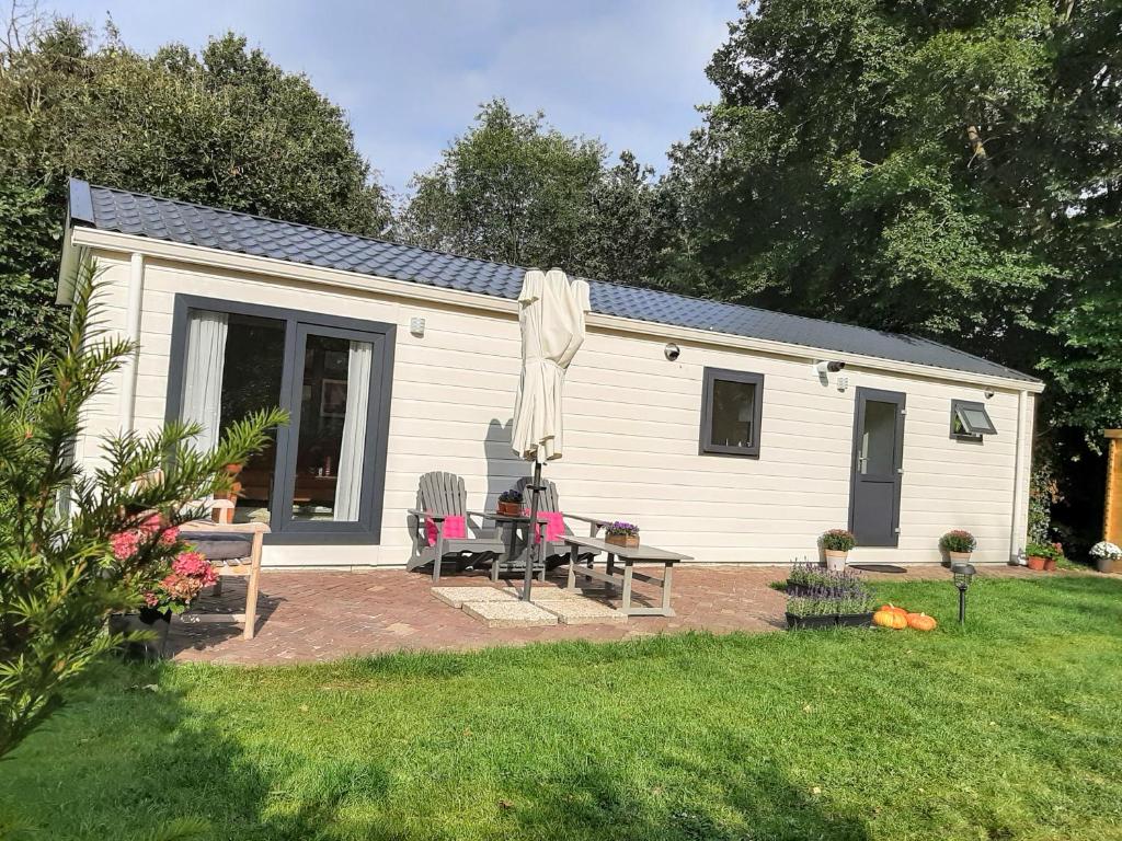 una pequeña casa blanca con mesa de picnic y sillas en De Woudtplaats, en Wolfheze