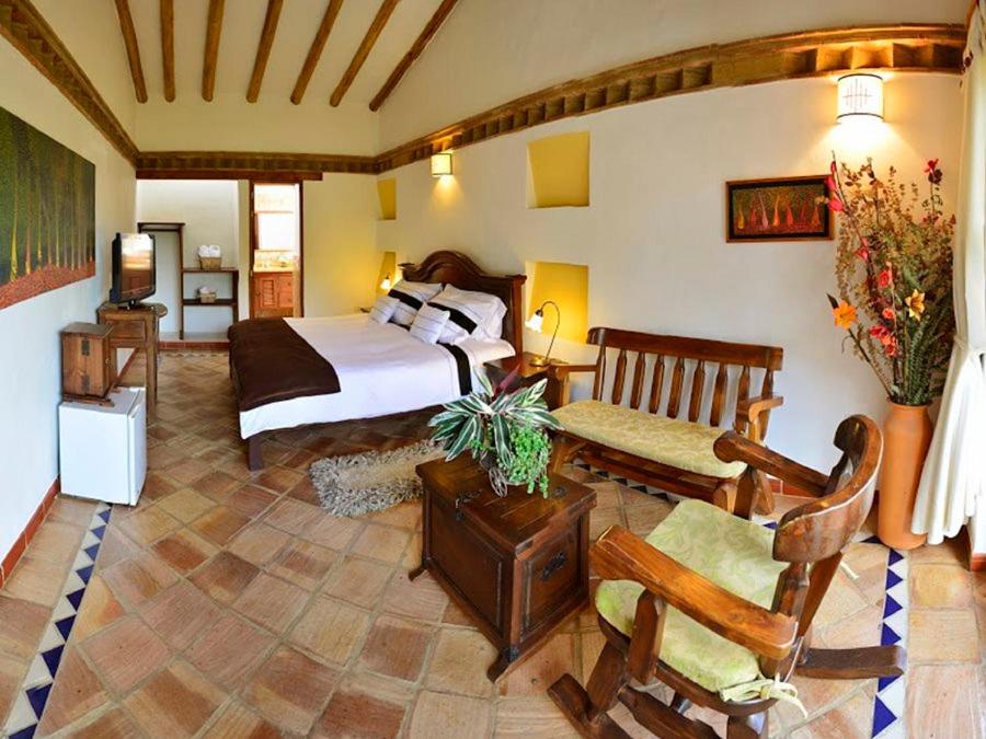 a bedroom with a bed and a living room at Hotel Boutique La Española in Villa de Leyva