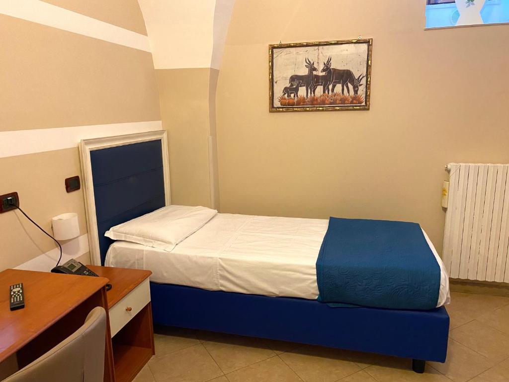 een slaapkamer met een bed en een bureau en een foto van paarden bij Albergo Ristorante del Cacciatore in Foggia