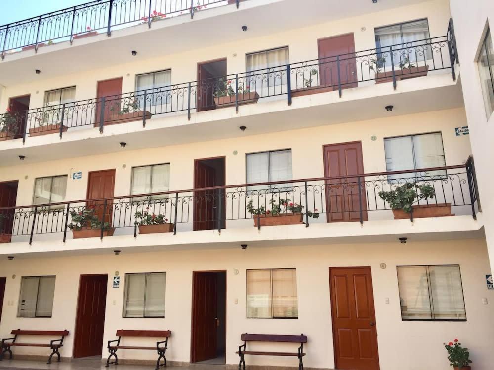 un grupo de edificios con balcones y bancos en Hostal La Casona, en Pisco