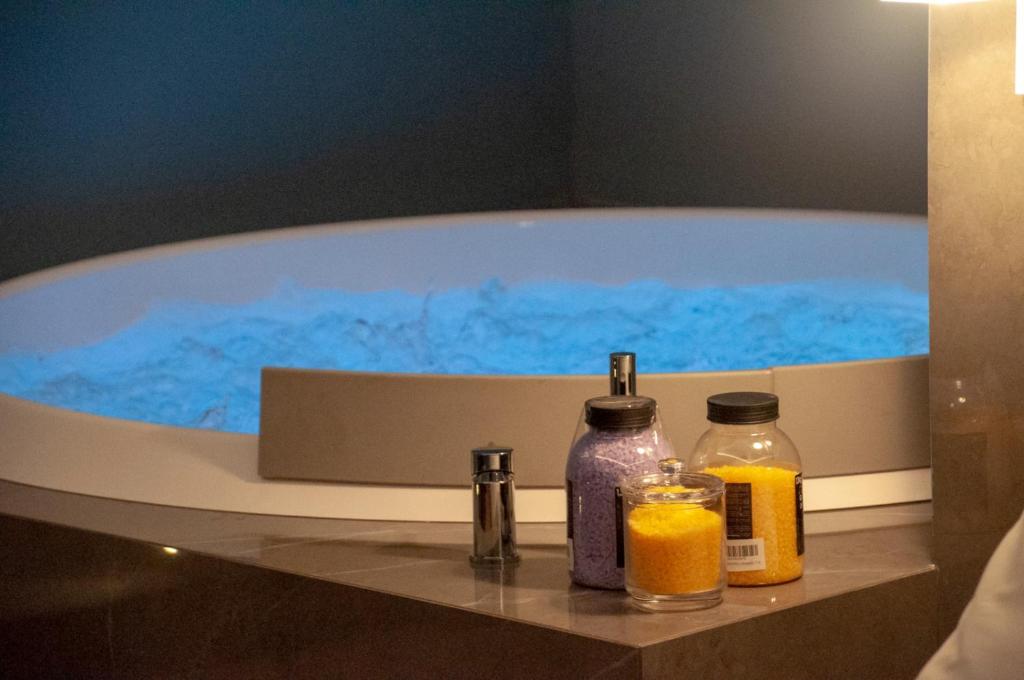a bath tub with blue water and two bottles of soap at FilHome 44 in Catania