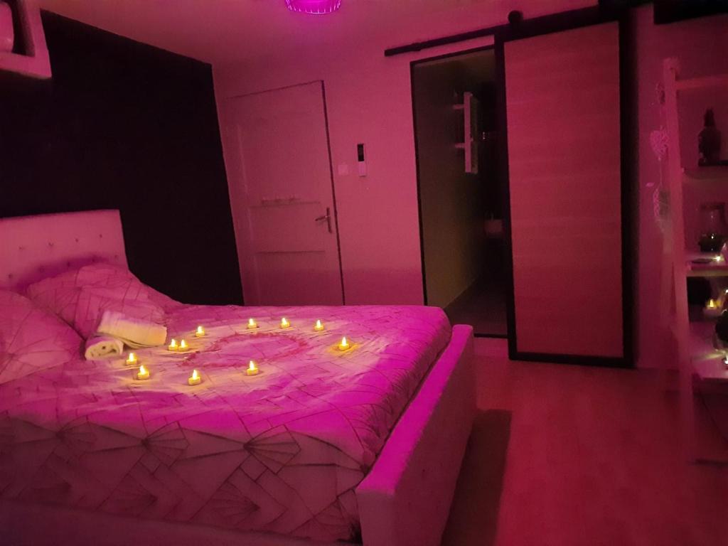 Un dormitorio rosa con una cama con velas. en Maison avec jacuzzi, en Saint-Mitre-les-Remparts