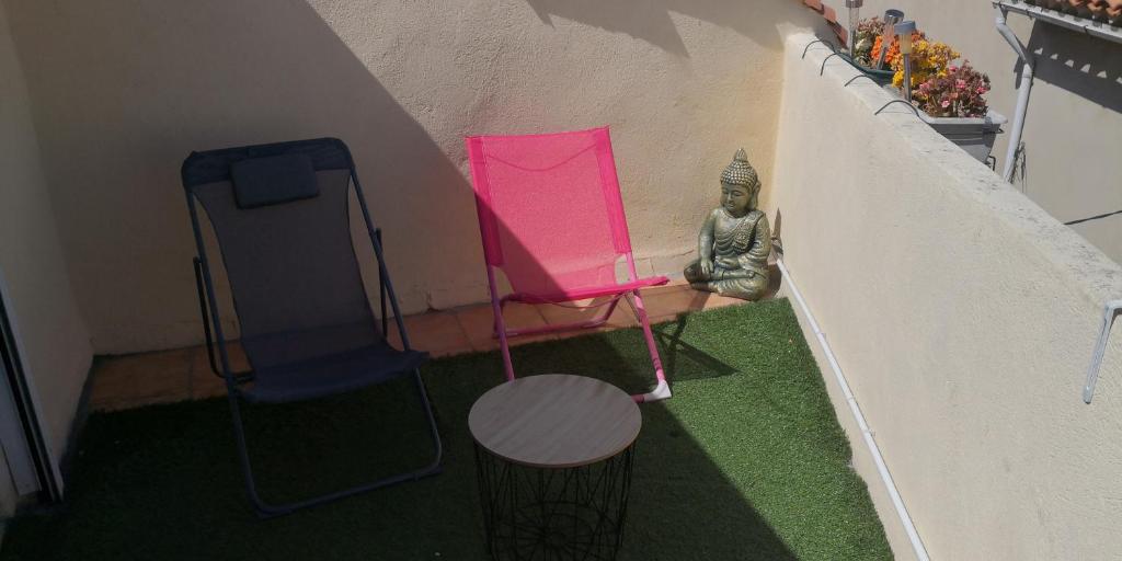Una pequeña habitación con una silla rosa y una estatua. en Maison avec jacuzzi, en Saint-Mitre-les-Remparts