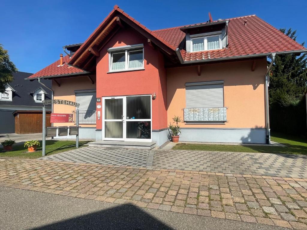 ein rotes und orangefarbenes Haus mit einer steinernen Einfahrt in der Unterkunft Haus Alexandra in Rust