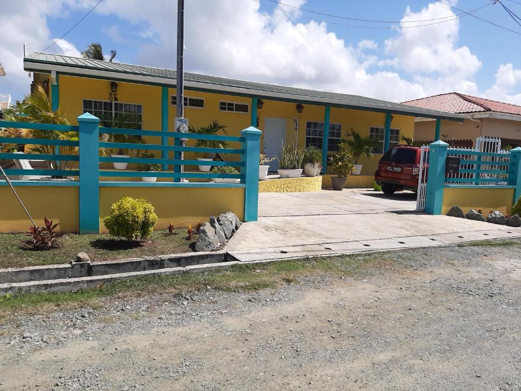 a yellow house with a blue railing in front of it at CC Best Villas Tobago in Lowlands