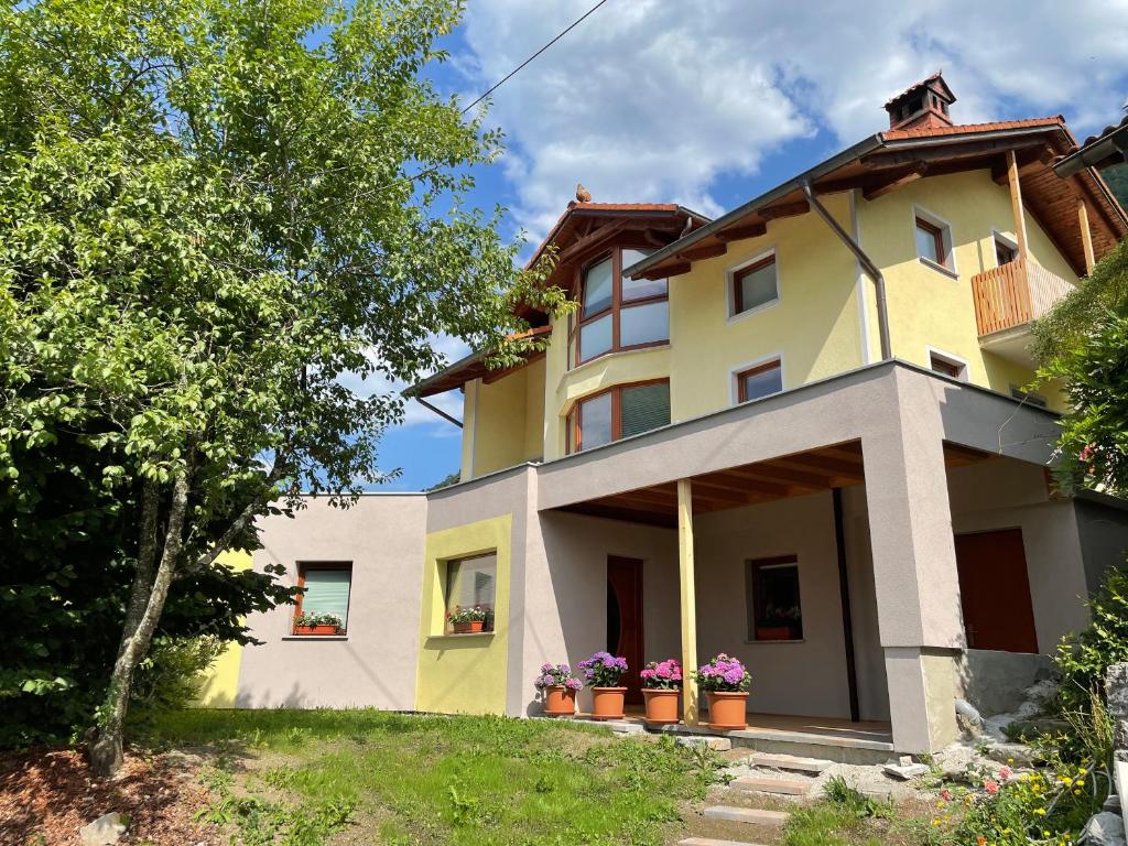 une maison jaune et blanche avec des fleurs dans les fenêtres dans l'établissement Apartma 7 - In the heart of Soča Valley, à Tolmin