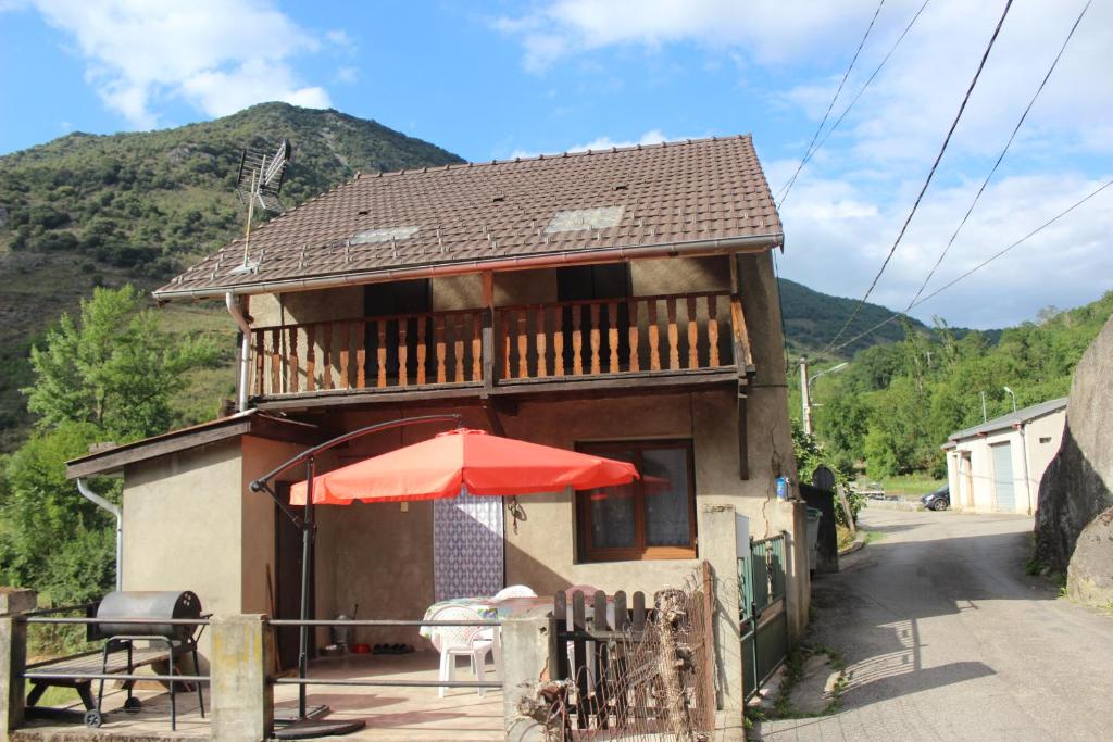una casa con una mesa y una sombrilla roja en Maison de charme calme entourée de montagne, en Ussat