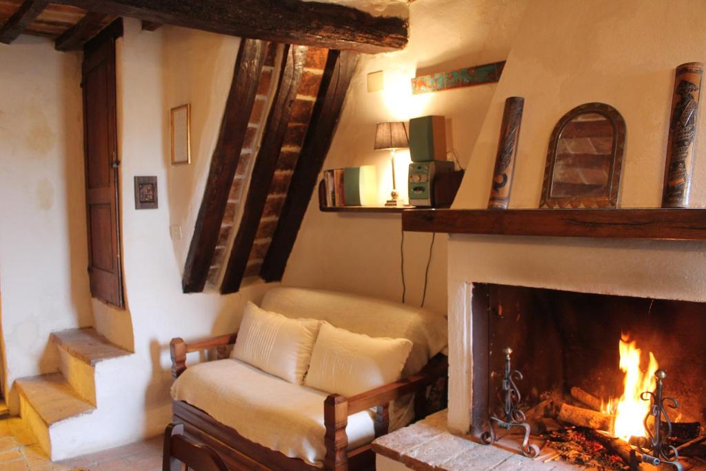 a living room with a fireplace and a chair at Petite Maison in Cetona