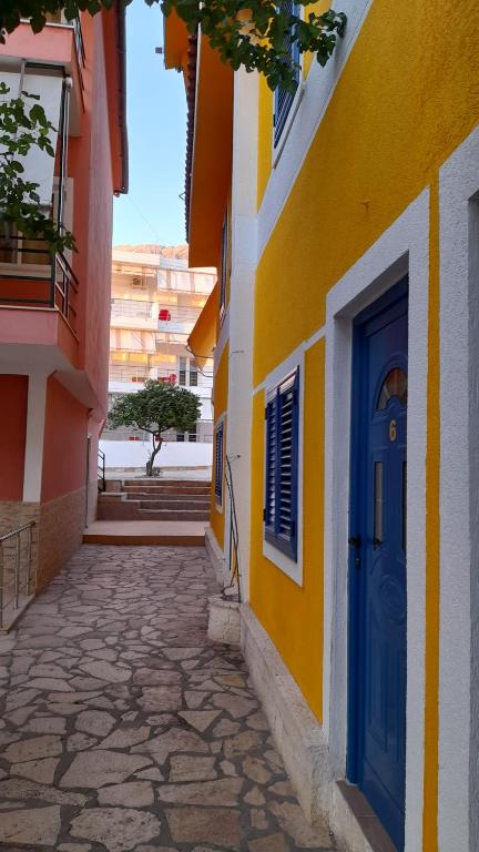 a yellow and blue building with a blue door at Hotel villa Petro in Dhërmi