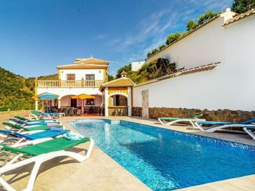 a villa with a swimming pool and lounge chairs at Belvilla by OYO Villa Javier in Sayalonga