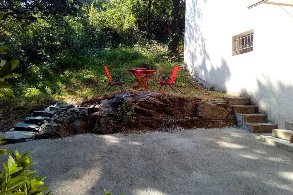 two red chairs and a table in a backyard at Duplex at the foothills of the Pyrenees in Geu