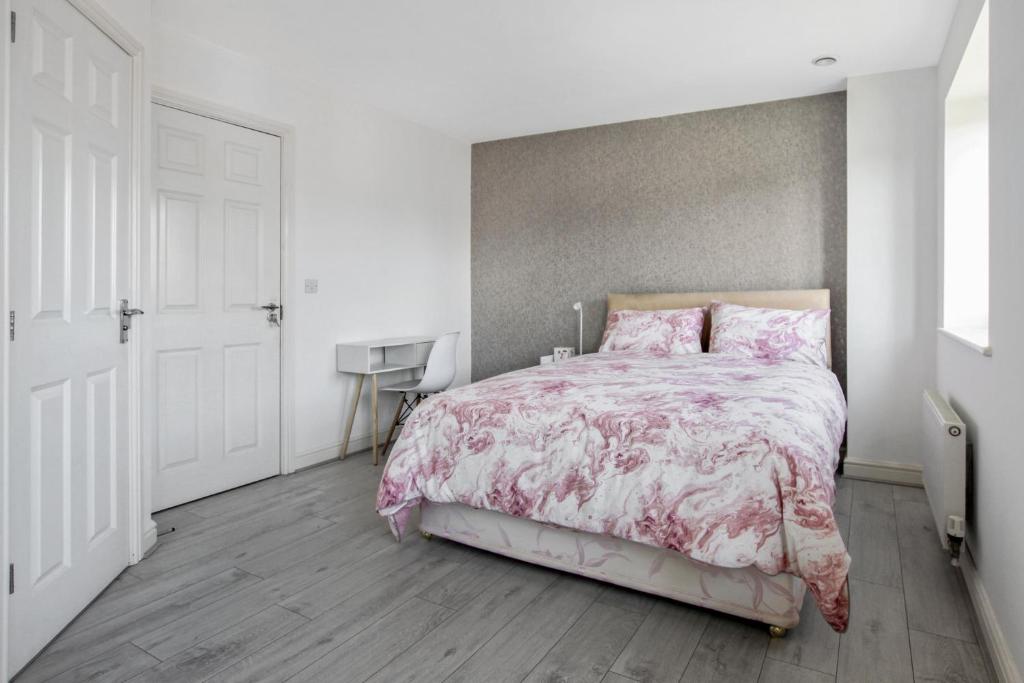 a bedroom with a bed with a pink comforter at Ruby Kingsize Bedroom with En-suite in Derby