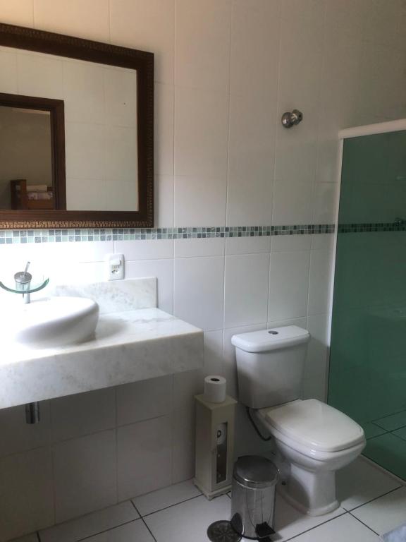 a bathroom with a sink and a toilet and a mirror at Suites Praia de Pernambuco in Guarujá