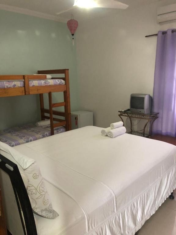 a bedroom with two bunk beds and a tv at Suites Praia de Pernambuco in Guarujá