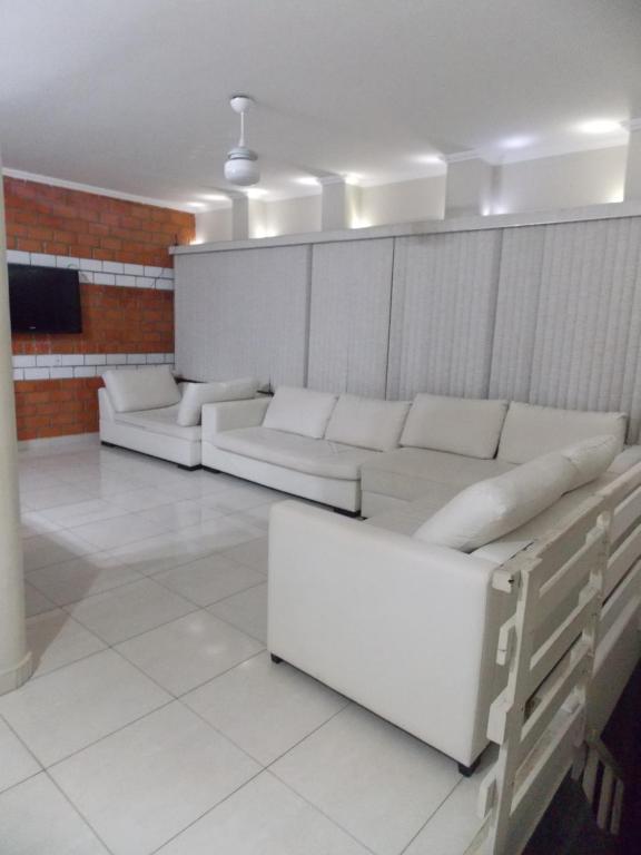 a living room with white couches and a tv at Apartamento Duplex Guarujá in Guarujá