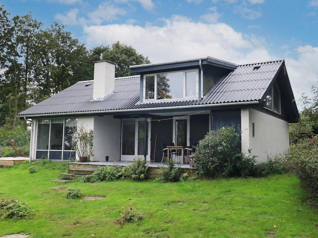 une maison blanche avec un toit noir sur une cour dans l'établissement Holiday home Roslev XVII, à Roslev