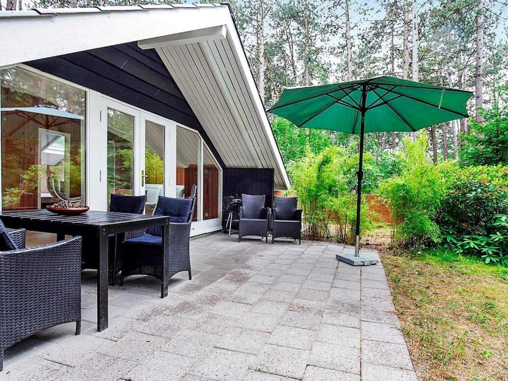 un patio con una mesa y una sombrilla verde en 7 person holiday home in Store Fuglede en Store Fuglede