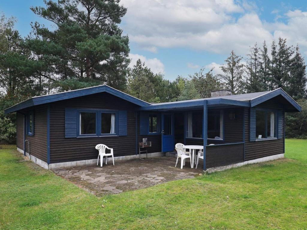 una casa azul con 2 sillas y una mesa en 5 person holiday home in H jslev, en Bøstrup