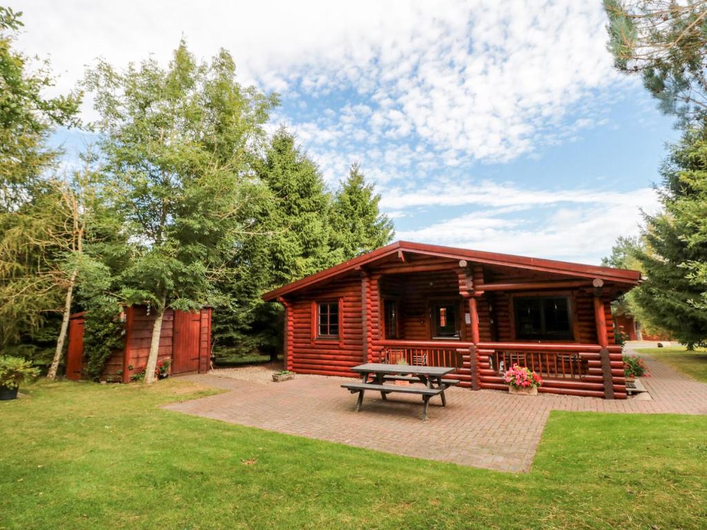 a log cabin with a picnic table in front of it at 23 Lakeside Drive in Morpeth