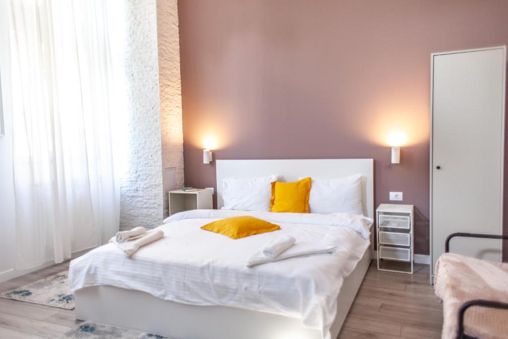 Un dormitorio con una gran cama blanca con almohadas amarillas. en Modern Studio in the Heart of Iasi, en Iaşi