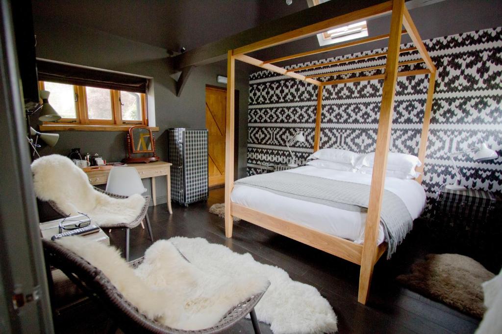 a bedroom with a canopy bed and two chairs at The White Horse in Chilgrove