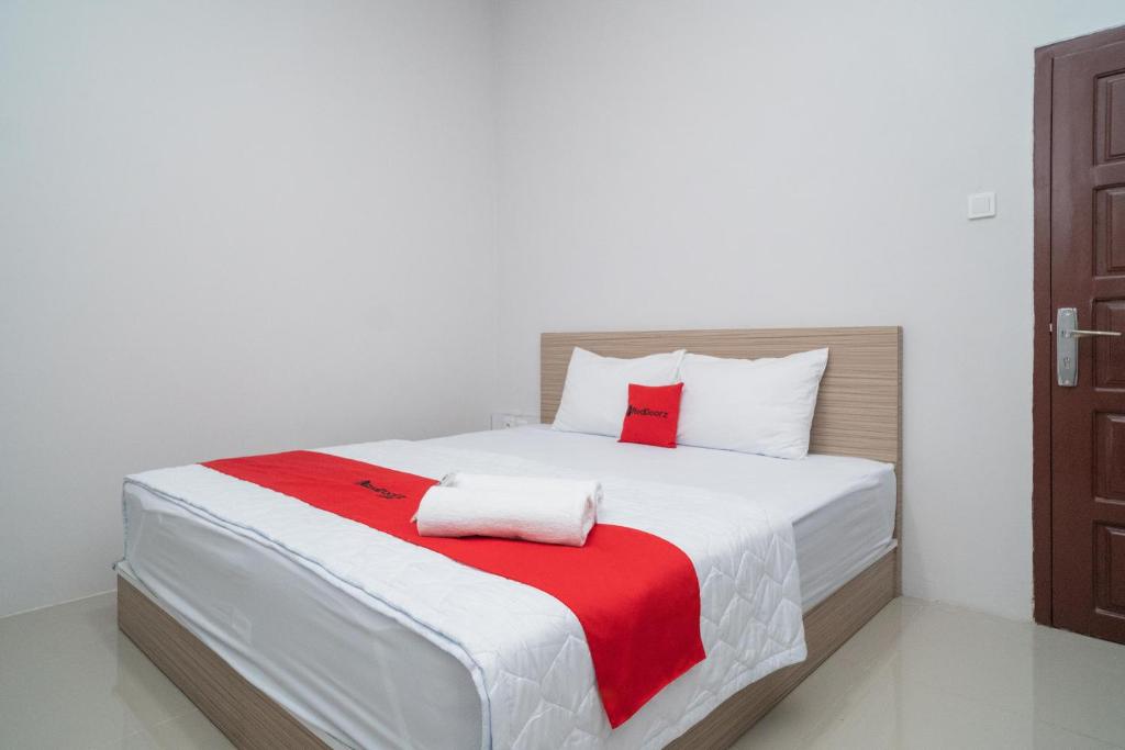 een slaapkamer met een bed met een rode en witte deken bij RedDoorz Syariah near Jalan Ahmad Yani Banjarmasin 3 in Sungai Lutus
