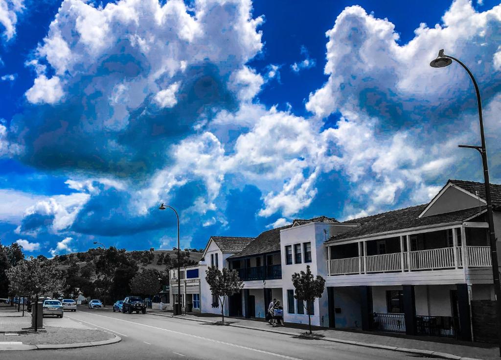 une rue avec des bâtiments et un ciel bleu avec des nuages dans l'établissement Toodyay Manor, à Toodyay