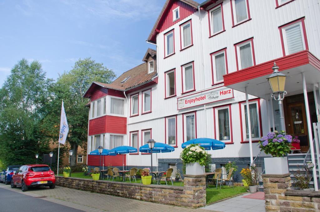 ein Gebäude mit Stühlen und Sonnenschirmen davor in der Unterkunft Hotel Harz in Hahnenklee-Bockswiese