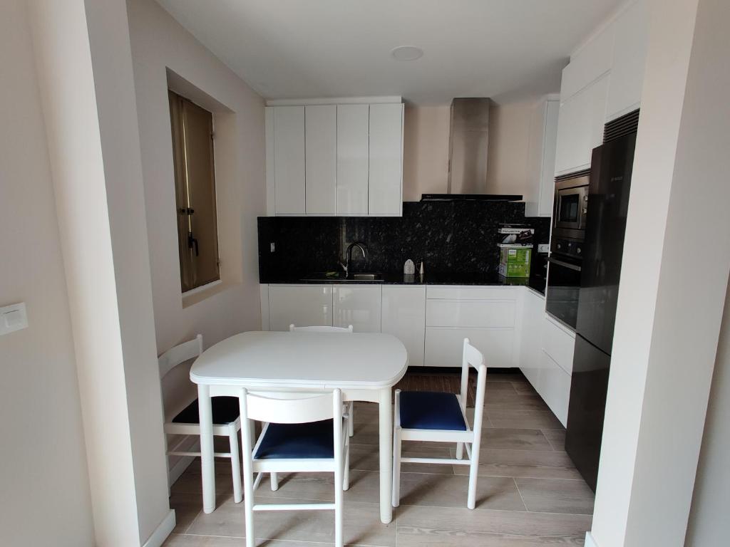 a white kitchen with a white table and chairs at La Portela Riverside in Redondela