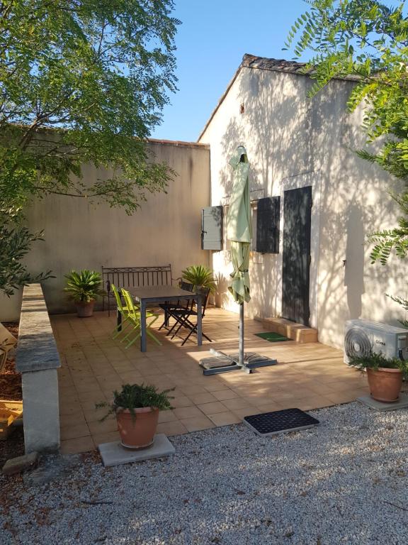 un patio con tavolo e panca accanto a un edificio di Appartement 2 pers avec accès piscine a Saint-Rémy-de-Provence